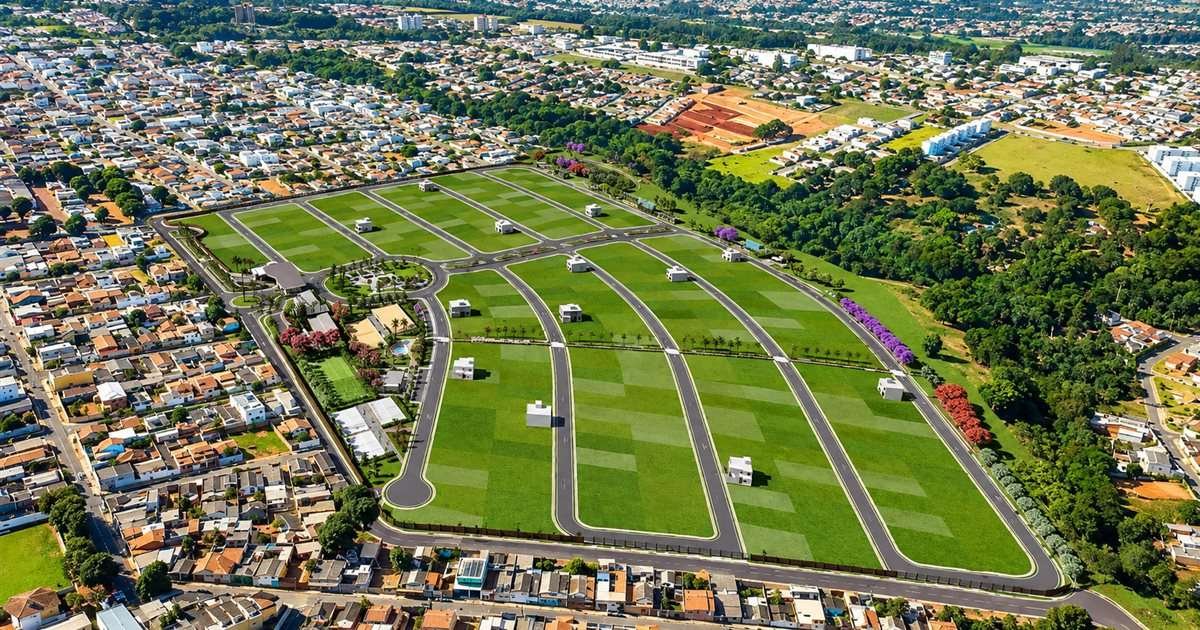 Vista aérea de um loteamento com quadras gramadas, vias asfaltadas e área de lazer, cercado por bairros residenciais e mata.