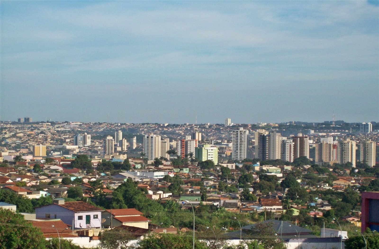 Vista de Anápolis com edifícios residenciais ao fundo, casas e árvores em primeiro plano.